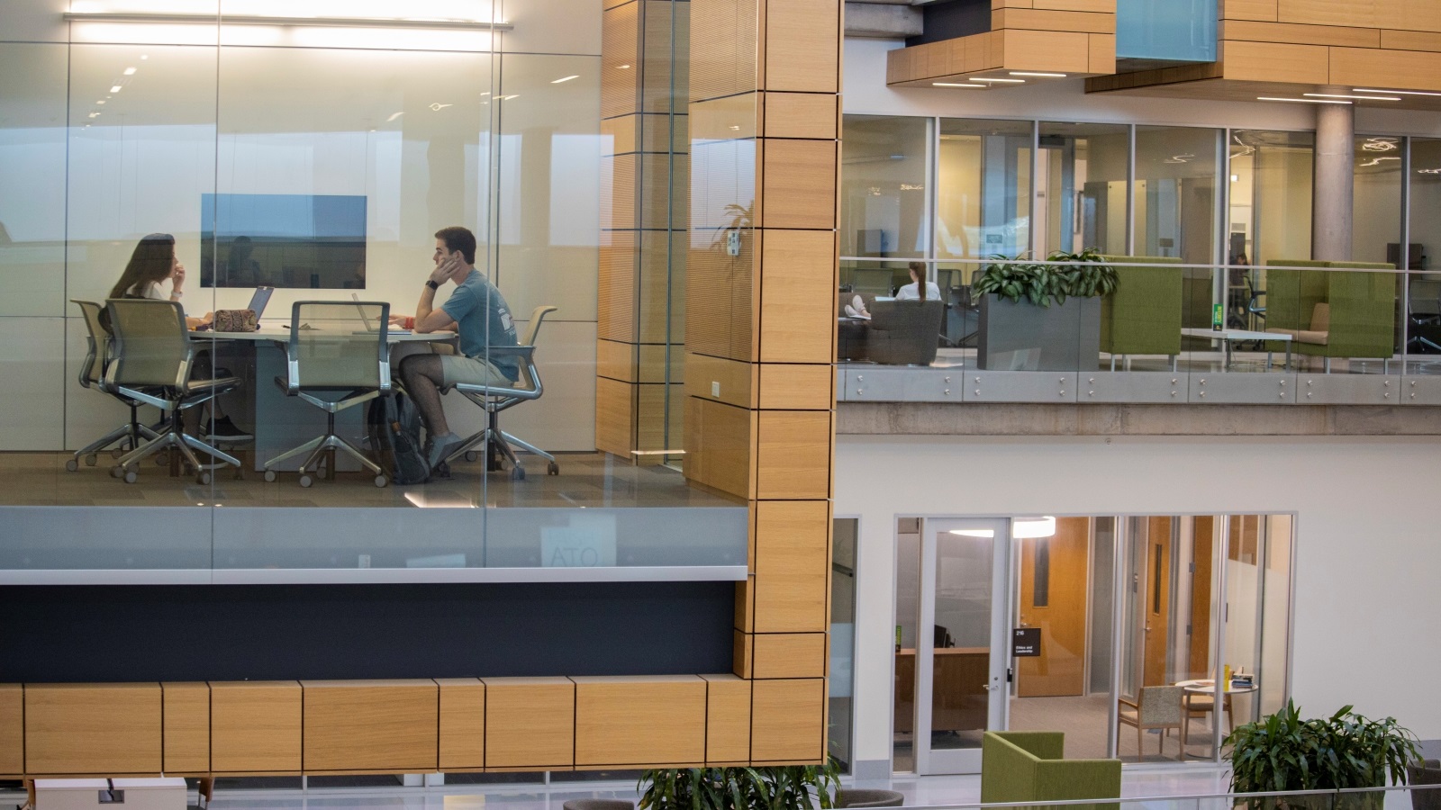 A male and female student in glass window study room inside Foster campus