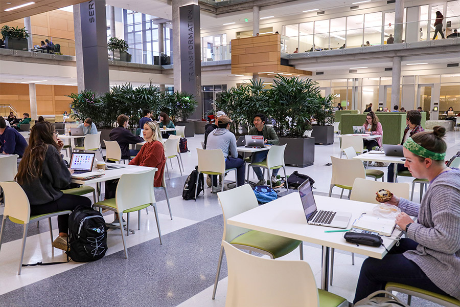 Interior view of the Foster Campus for Business and Innovation on the Baylor University campus atrium with groups of students working at multiple tables