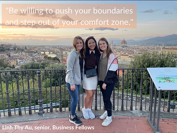Three young women in front of a foreign city hillside with quote that says, "Be willing to push your boundaries and step out of your comfort zone." Quote attributed to Linh Thy Au, senior, Business Fellows