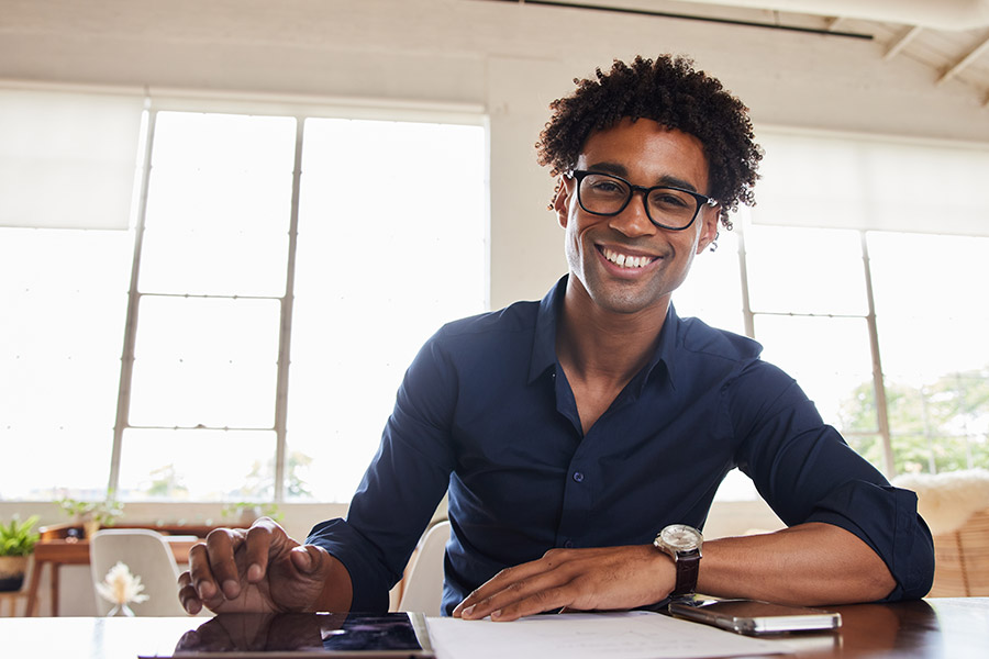 smiling young businessman working on a tablet and going over paperwork at a table in an office