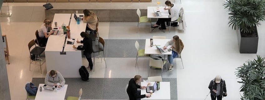 a group of students sitting around a table at the first floor of the Foster Campus