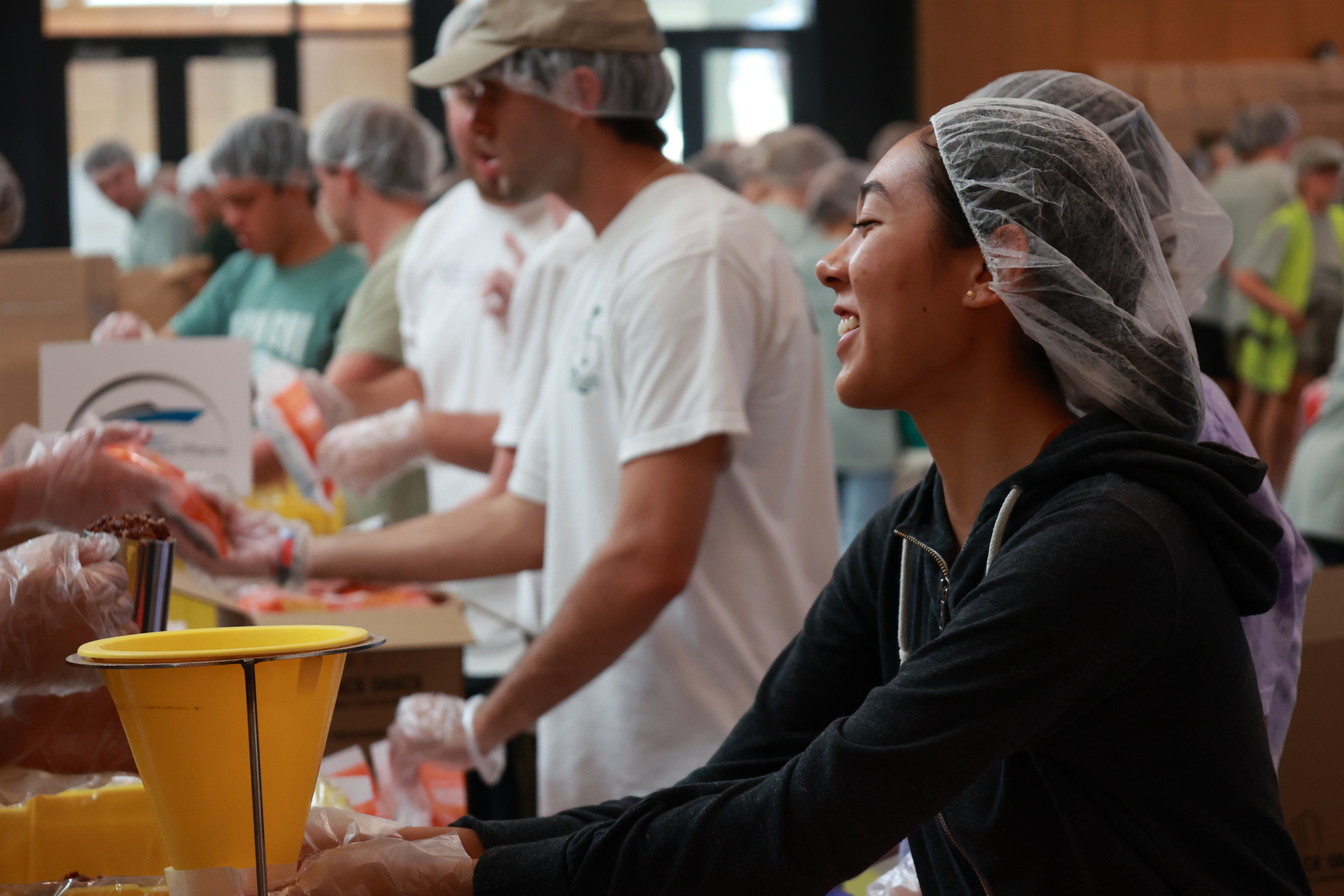 Smiling Woman packing meals for 58:10 Project