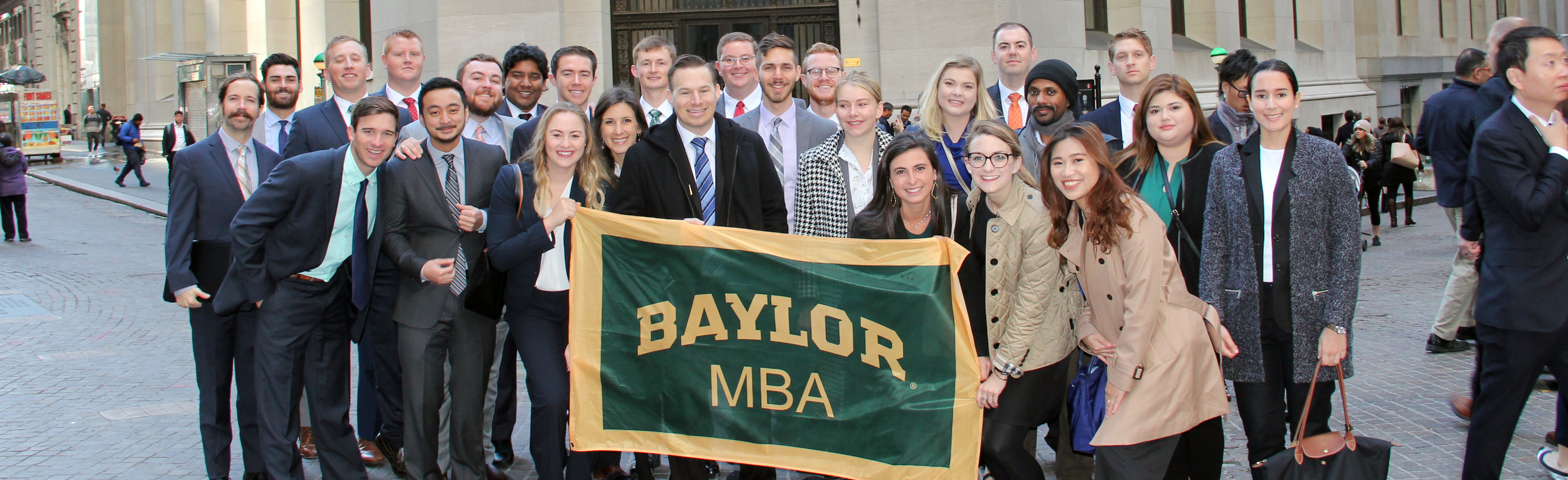 Baylor MBA students holding a Baylor MBA flag