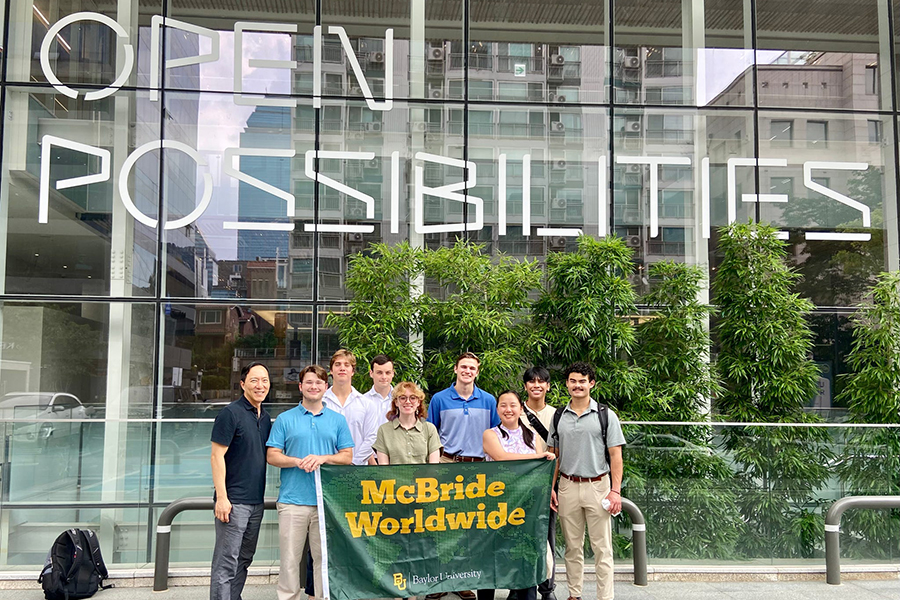 group of students holding "McBride Worldwide" flag