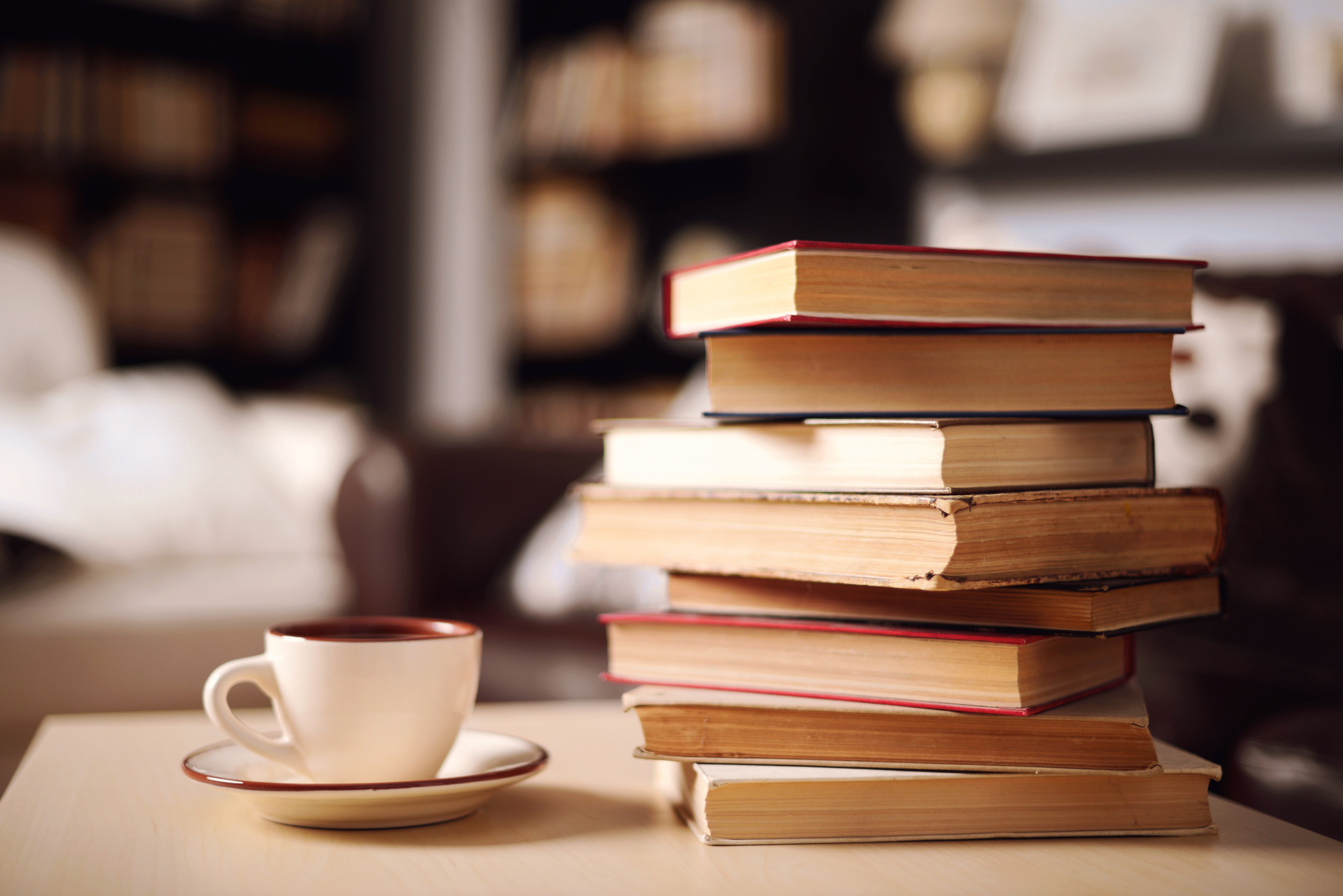 Stack of books next to coffee mug on table