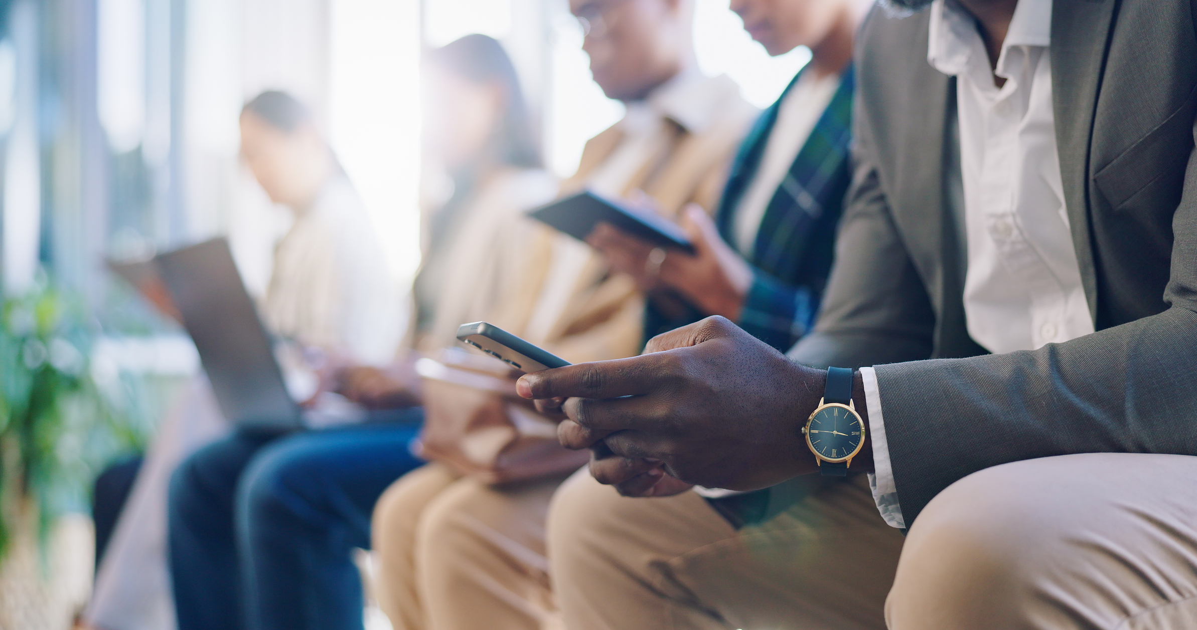 Professionals seated in a row each looking at a digital device