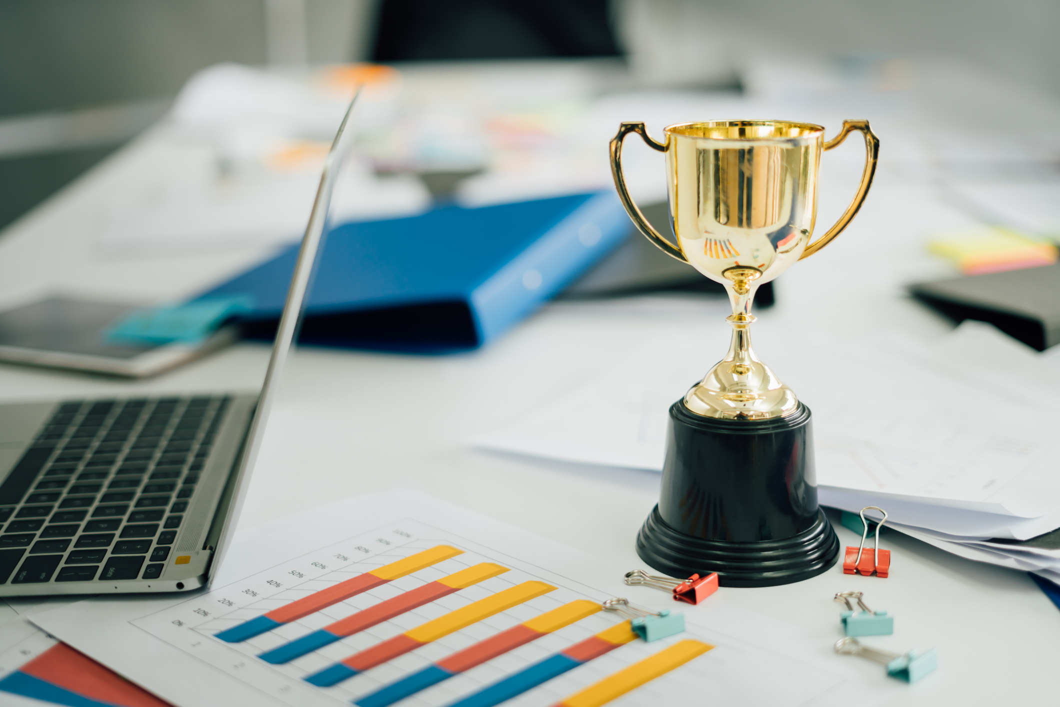 An award on a desk with graphs and a laptop