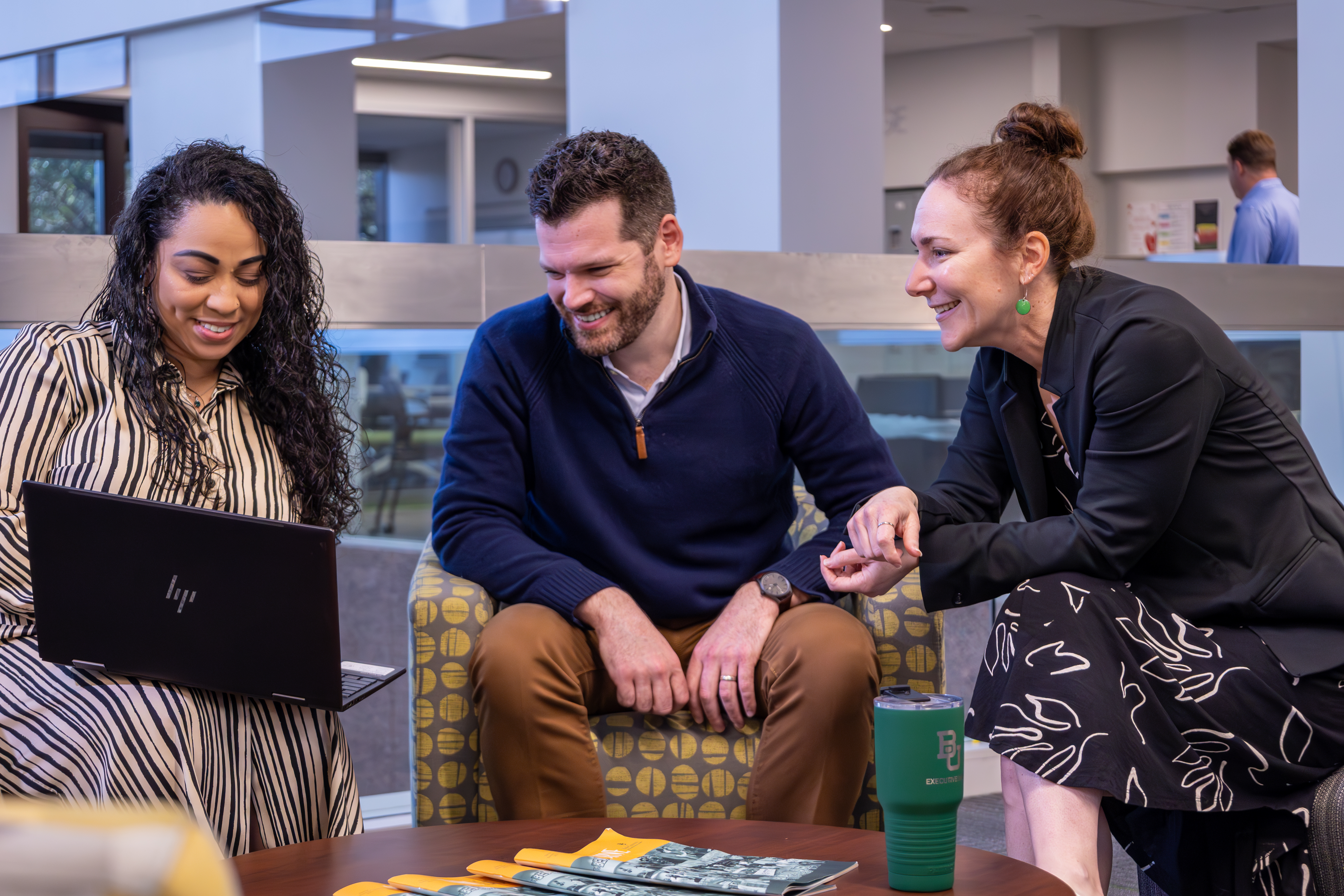 Three MBA students looking at a laptop together