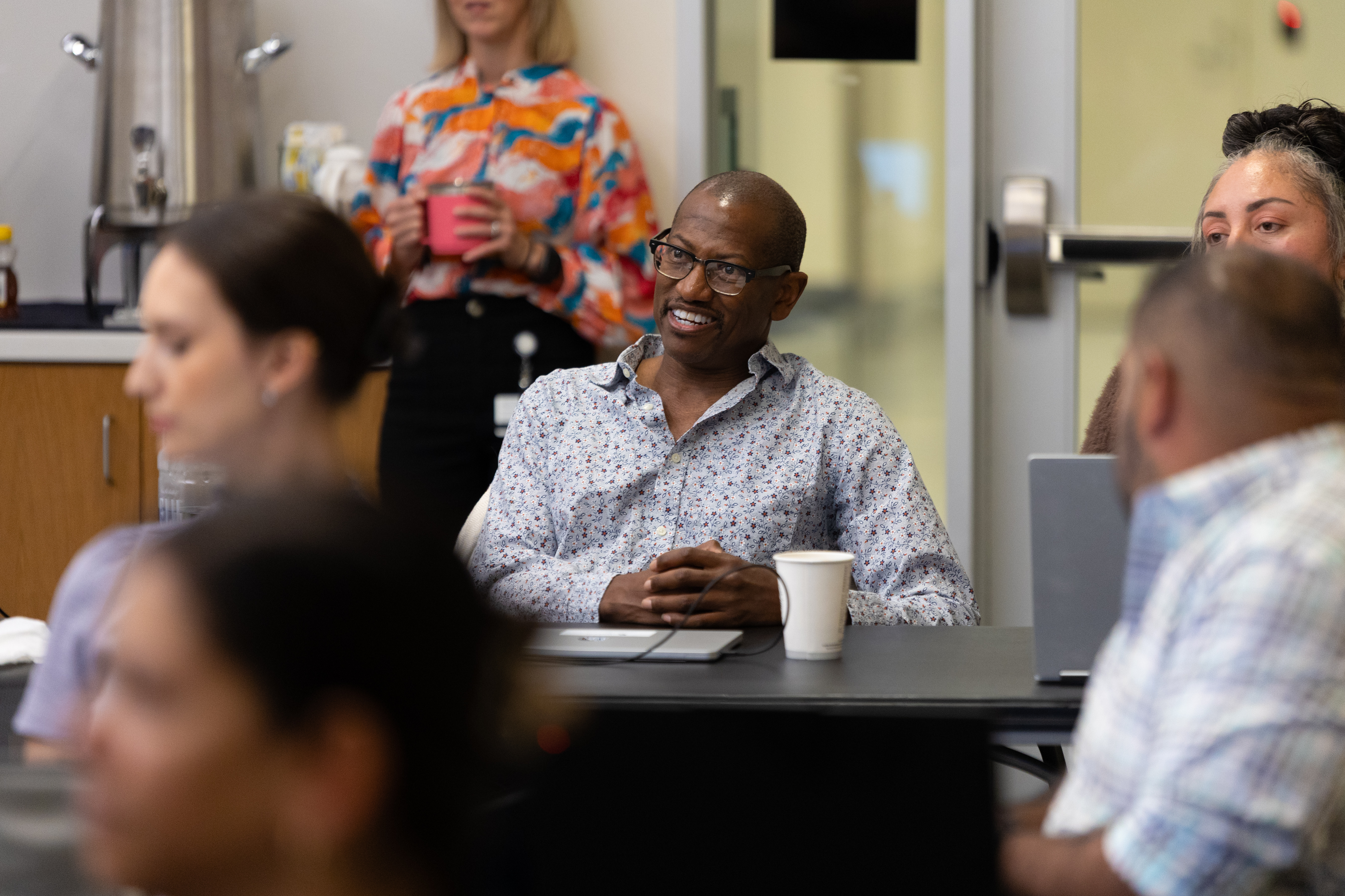 Business professional in an executive MBA classroom, smiling while seated at a table