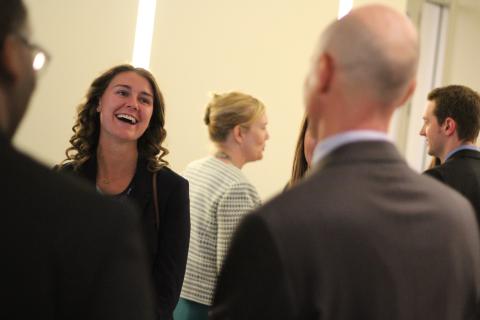 Woman wearing professional attire laughing and facing a man who has his back to the camera