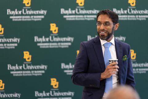 Dean Mazumder with coffee in hand talking to faculty