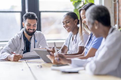 Group of medical residents around a conference table smiling