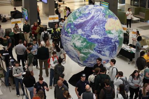 Global Business Expo - Spring 2026 with a giant inflatable globe in the middle of an atrium surrounded by students talking with faculty
