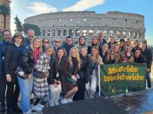 McBride - European Business Seminar Winter students holding flag in front of Roman Colosseum 