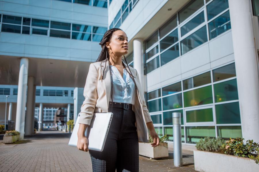 Female business professional returning to work with a laptop in hand