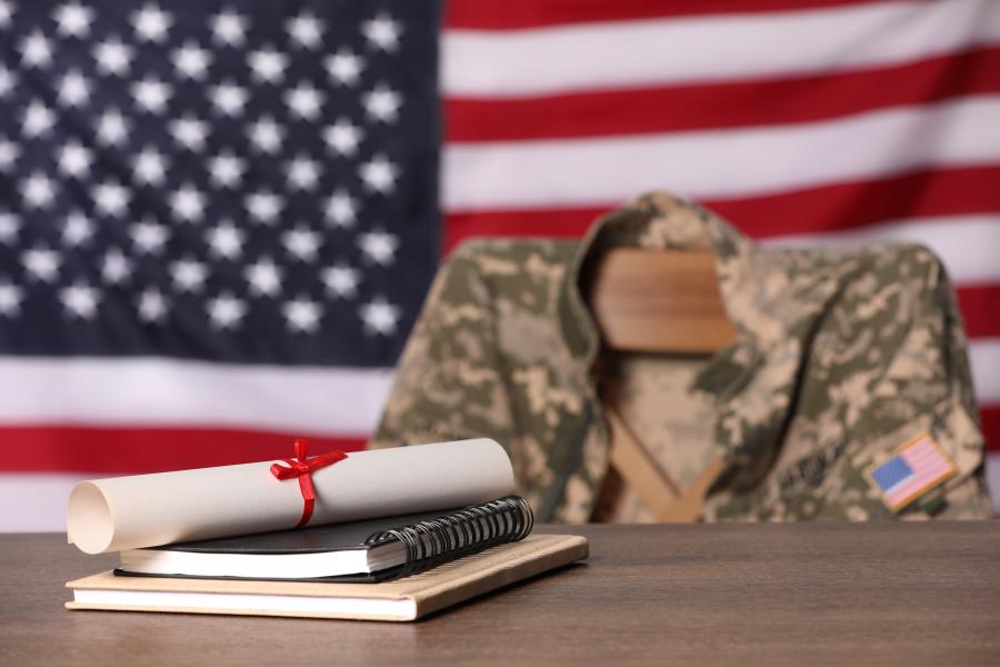 Diploma on a table with a military uniform and American flag out of focus